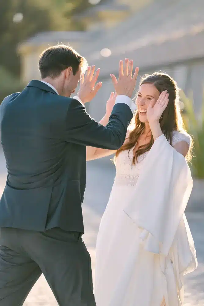 Brautpaar macht ein High Five im warmen Gegenlicht vor der Orangerie im Schlosspark Eisenstadt