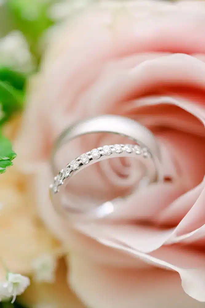 Zwei Eheringe liegen in einer rosafarbenen Rosenblüte, Detailfoto der Hochzeit in der Orangerie im Schlosspark Eisenstadt