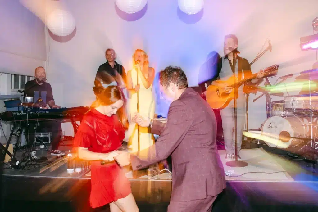 Hochzeitsgäste tanzen vor der Bühne der Live-Band im bunten Licht, Hochzeitsparty in der Orangerie im Schlosspark Eisenstadt