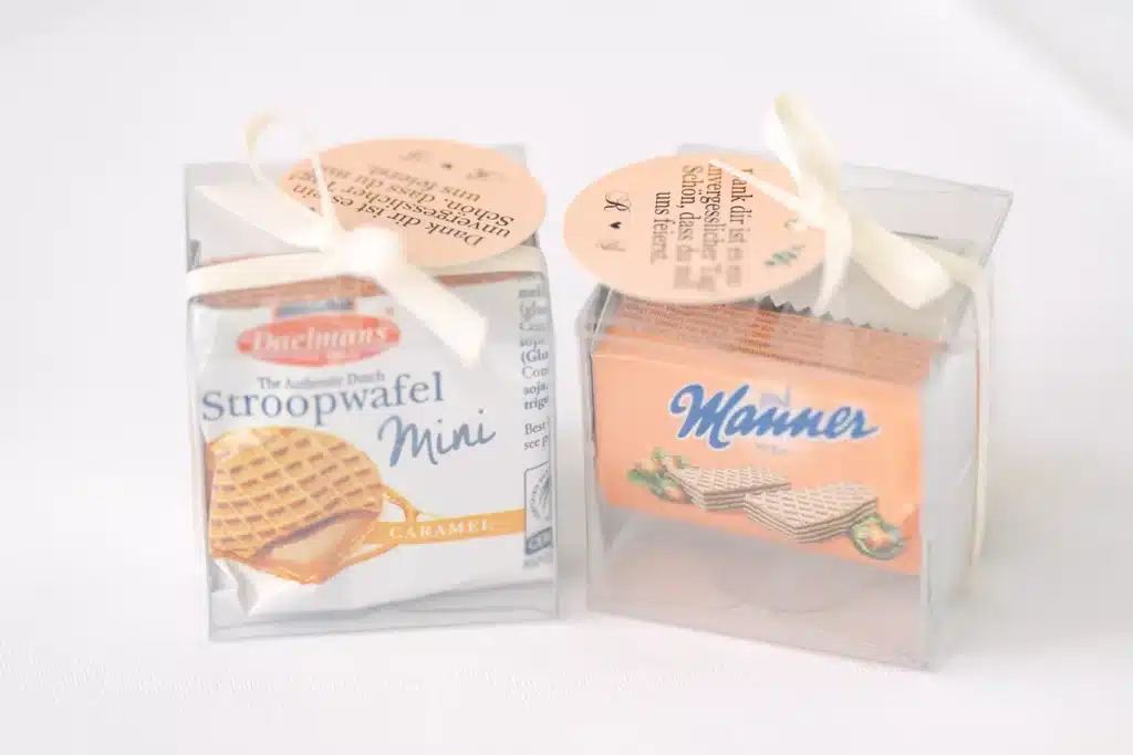 Gastgeschenke in kleinen durchsichtigen Boxen mit Schleife und Anhänger auf der Hochzeitstafel in der Orangerie Eisenstadt
