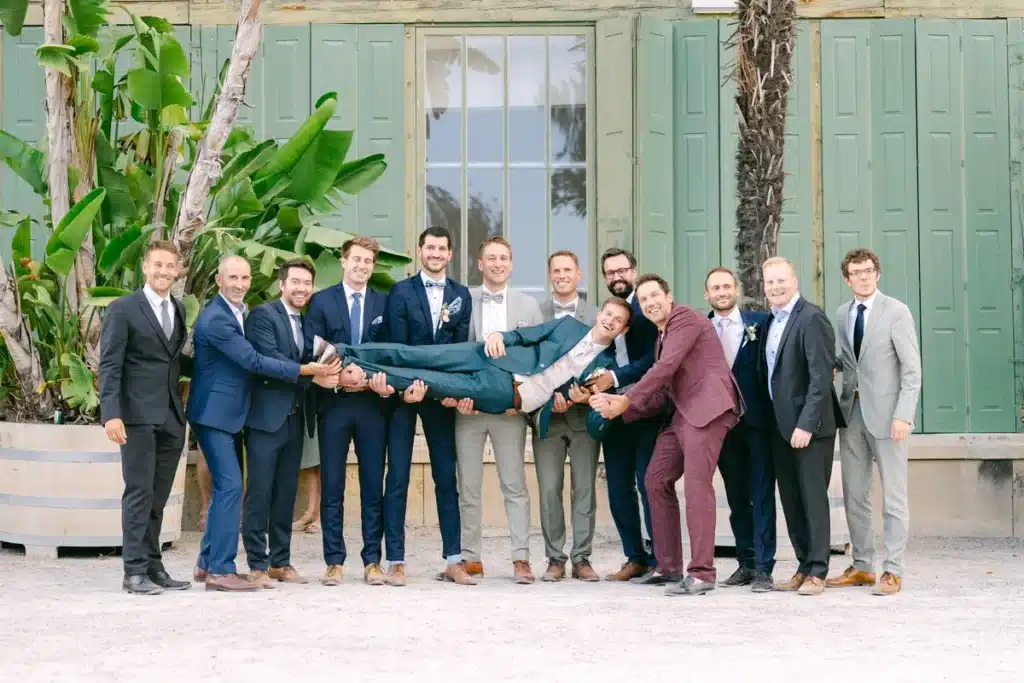 Gruppenfoto der männlichen Hochzeitsgäste in Anzügen vor den grünen Fensterläden der Orangerie im Schlosspark Eisenstadt