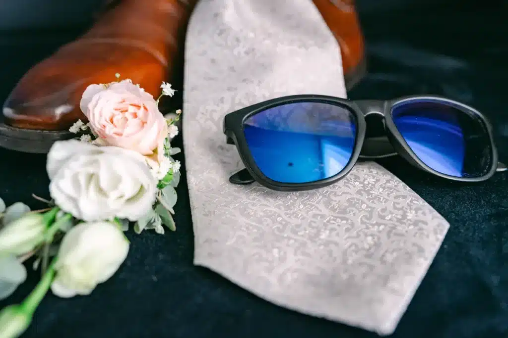 Krawatte, Sonnenbrille, Ansteckblume und brauner Lederschuh des Bräutigams als Detail, Hochzeit in der Orangerie im Schlosspark Eisenstadt