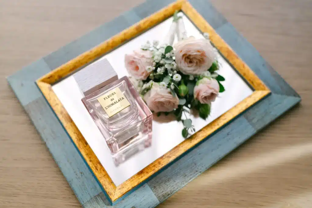Parfumflasche der Braut mit rosafarbenen Rosen auf einem goldenen Tablett, Detail vom Getting Ready zur Hochzeit in der Orangerie im Schlosspark Eisenstadt