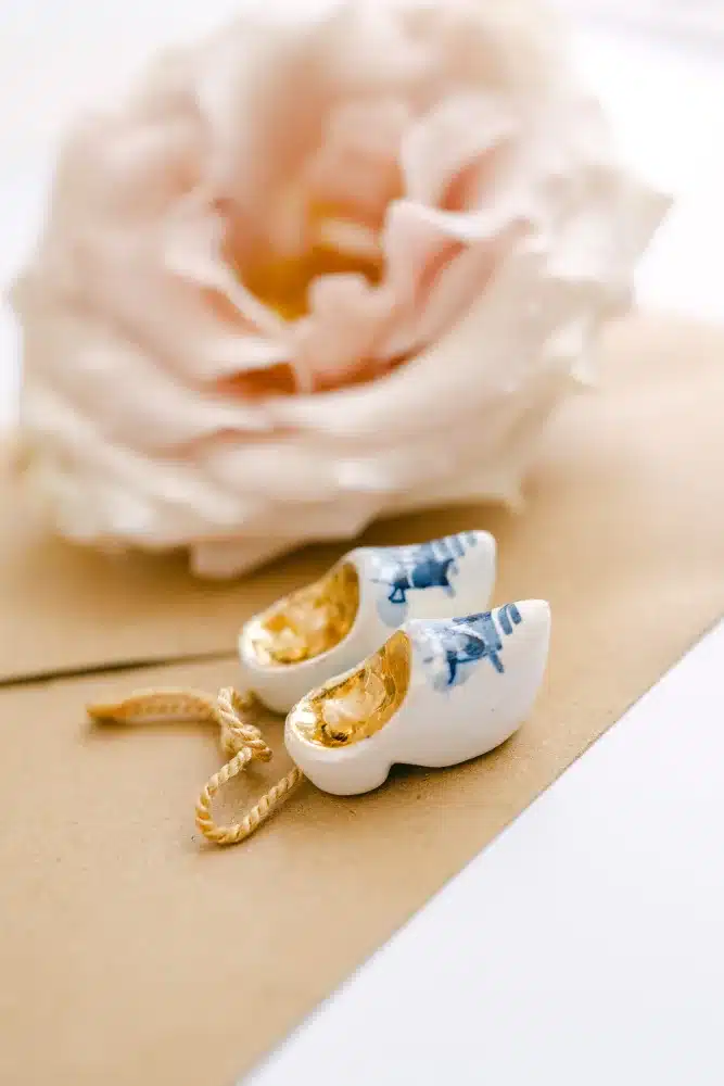 Zartrosa Rosenblüte neben zwei kleinen blau-weißen Porzellan-Holzschuhen, Detailfoto vom Heiraten in der Orangerie im Schlosspark Eisenstadt