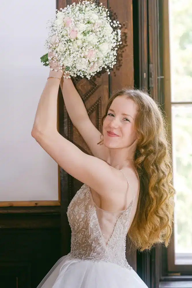 Heiraten in der Hochzeitslocation Schloss Margarethen am Moos – Feier, Hochzeitstanz und Party: Braut hebt ihren Brautstrauß über den Kopf