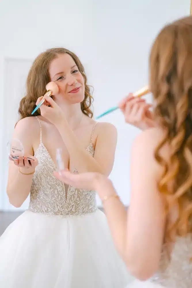 Heiraten in der Hochzeitslocation Schloss Margarethen am Moos – Getting Ready: Braut trägt Rouge auf, Nahaufnahme der Hände vor dem Spiegel