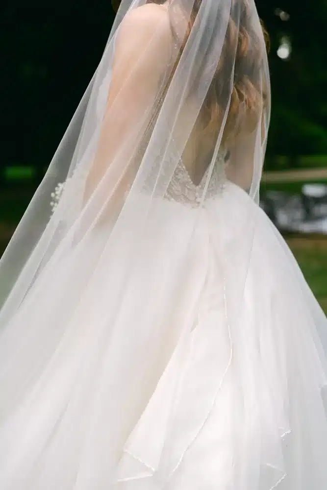Heiraten in der Hochzeitslocation Schloss Margarethen am Moos – Brautpaarshooting: Brautpaar geht händchenhaltend an einer Weide entlang