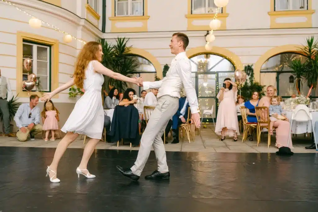 Heiraten in der Hochzeitslocation Schloss Margarethen am Moos – Feier, Hochzeitstanz und Party: Brautpaar tanzt Swing vor applaudierenden Gästen