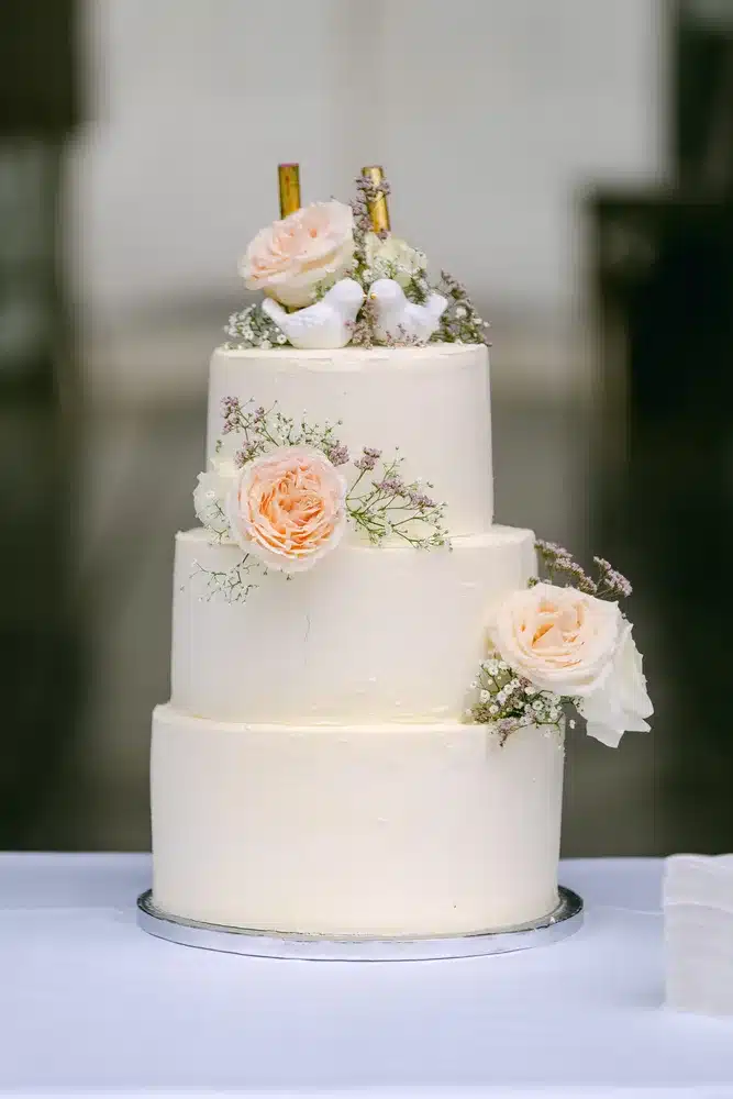 Heiraten in der Hochzeitslocation Schloss Margarethen am Moos – Feier, Hochzeitstanz und Party: Dreistöckige Hochzeitstorte mit Pfingstrosen dekoriert