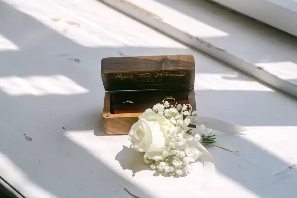 Heiraten in der Hochzeitslocation Schloss Margarethen am Moos – Details und Vorbereitungen: Eheringe in einer gravierten Holzbox mit einer Rose