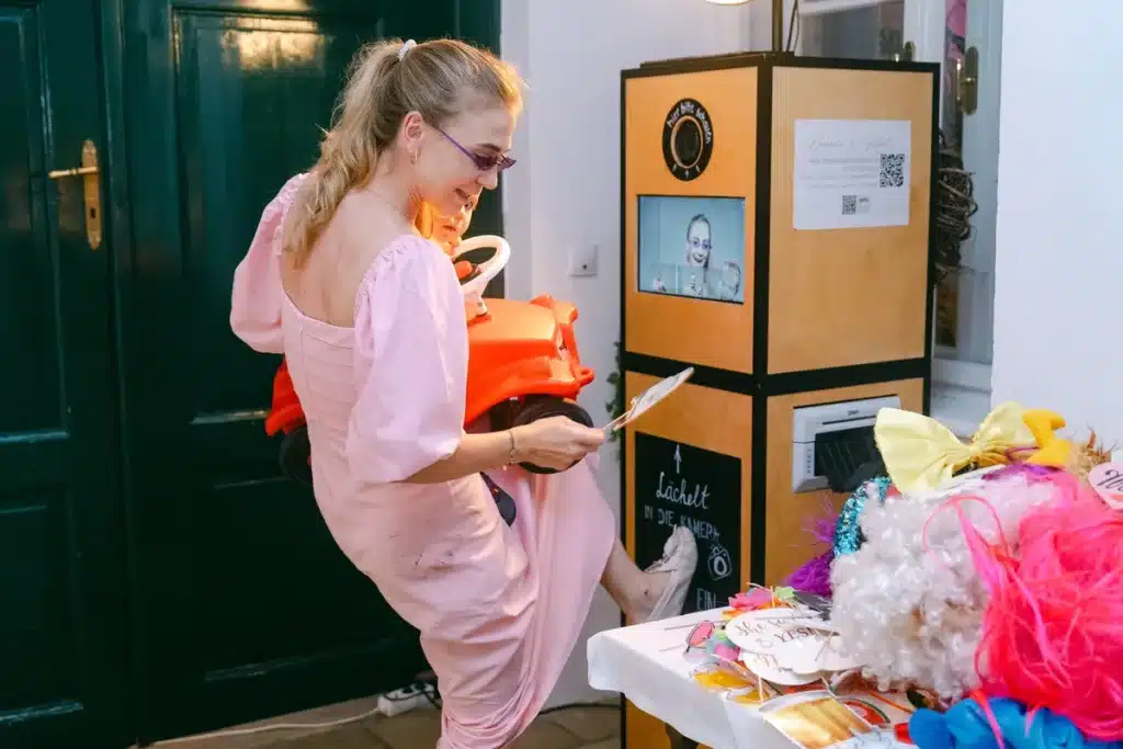 Heiraten in der Hochzeitslocation Schloss Margarethen am Moos – Feier, Hochzeitstanz und Party: Frau im rosa Overall an der Fotobox