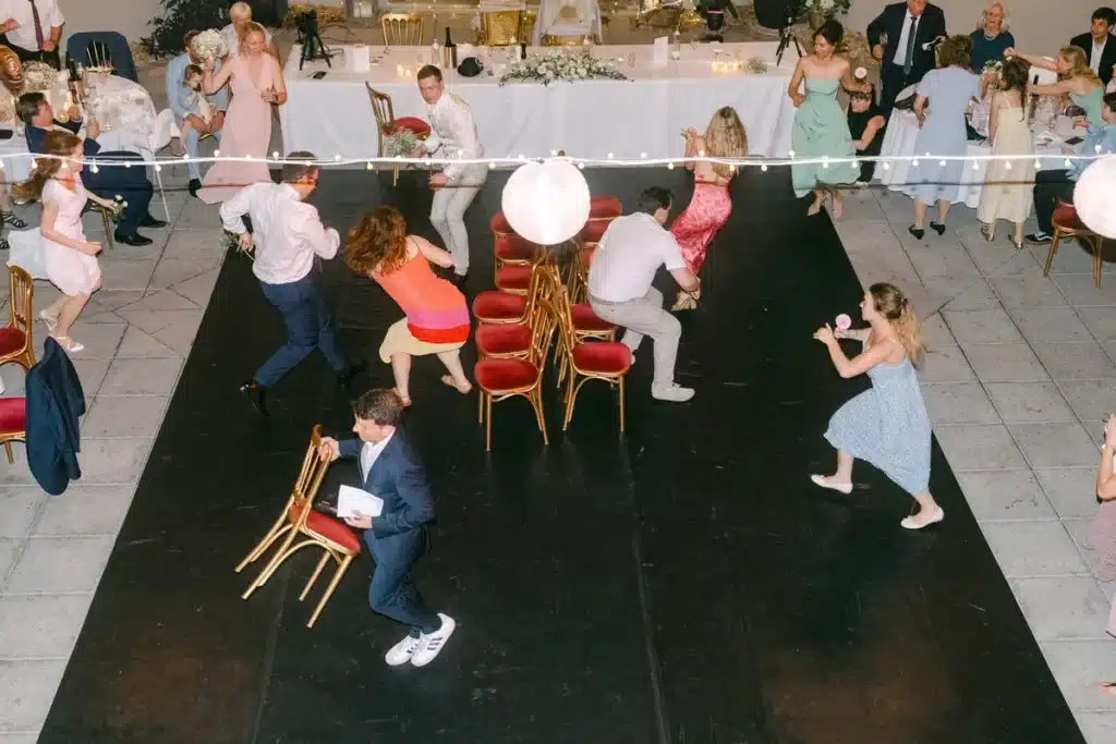 Heiraten in der Hochzeitslocation Schloss Margarethen am Moos – Feier, Hochzeitstanz und Party: Gäste springen beim Stuhltanz, Ansicht von oben