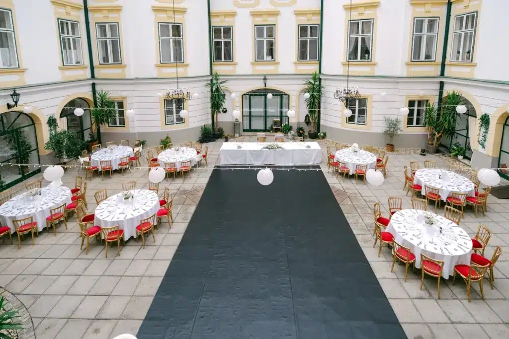 Heiraten in der Hochzeitslocation Schloss Margarethen am Moos – Feier, Hochzeitstanz und Party: Innenhof mit Tanzfläche und Haupttisch von oben fotografiert