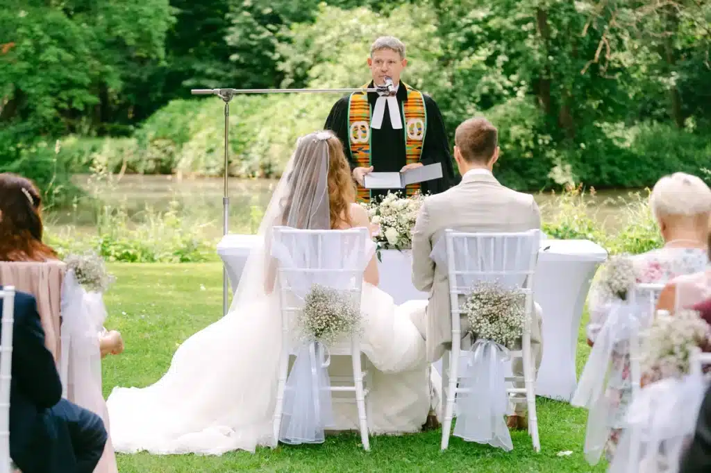Heiraten in der Hochzeitslocation Schloss Margarethen am Moos – Trauung: Pfarrer hält Traurede am Seeufer