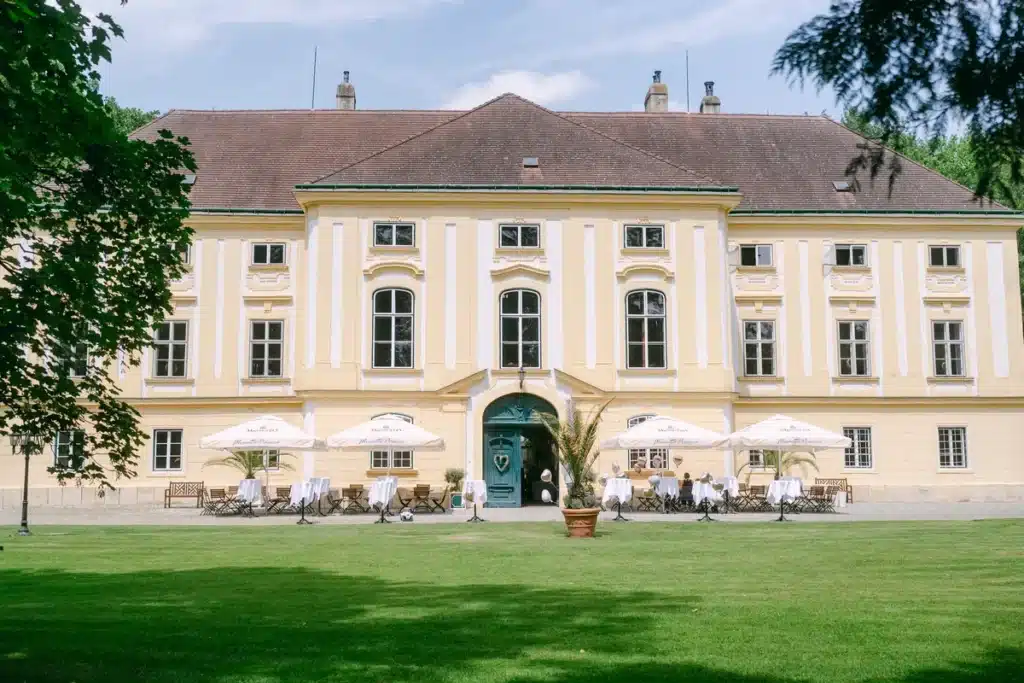 Heiraten in der Hochzeitslocation Schloss Margarethen am Moos – Details und Vorbereitungen: Schlossfassade mit Terrasse und aufgespannten Sonnenschirmen