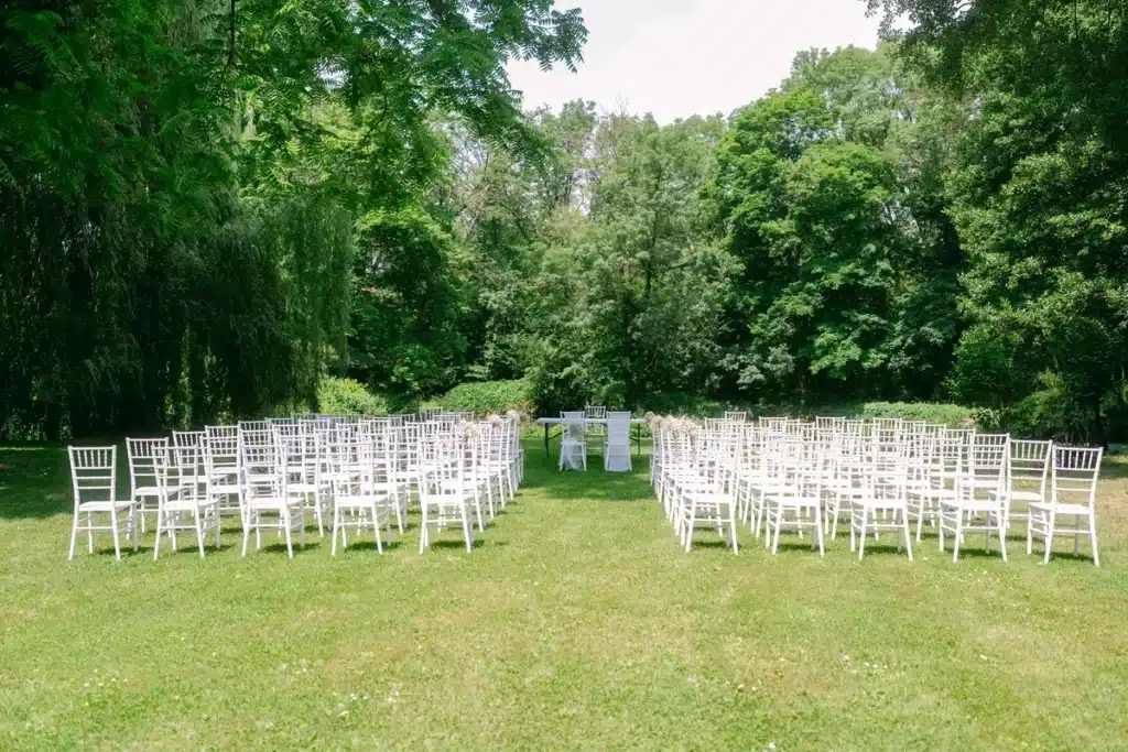 Heiraten in der Hochzeitslocation Schloss Margarethen am Moos – Details und Vorbereitungen: Weiße Stuhlreihen für die Trauung im Schlosspark aufgestellt