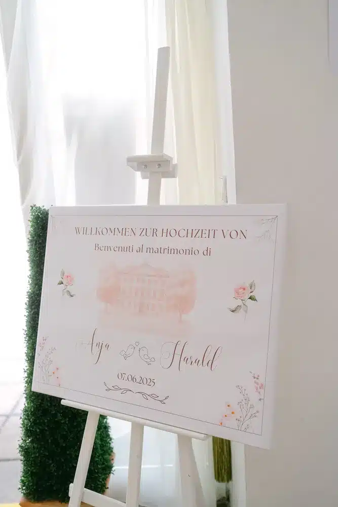 Heiraten in der Hochzeitslocation Schloss Margarethen am Moos – Details und Vorbereitungen: Willkommensschild auf Holzstaffelei mit Schlossmotiv für die Hochzeitsgäste