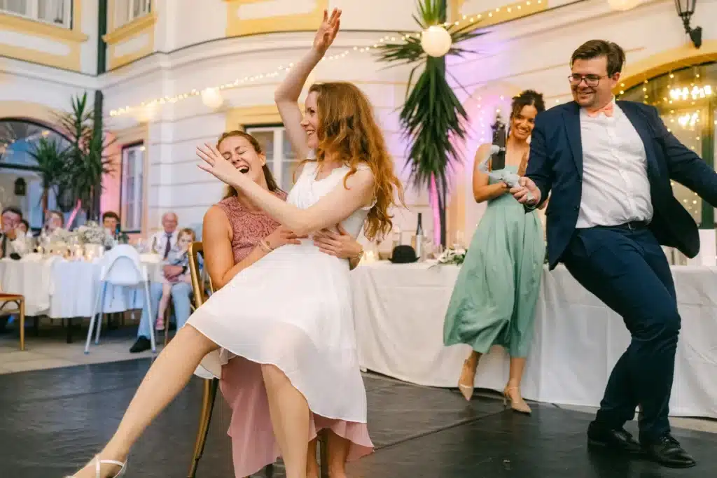 Heiraten in der Hochzeitslocation Schloss Margarethen am Moos – Feier, Hochzeitstanz und Party: Zwei Frauen tanzen ausgelassen neben einem tanzenden Mann