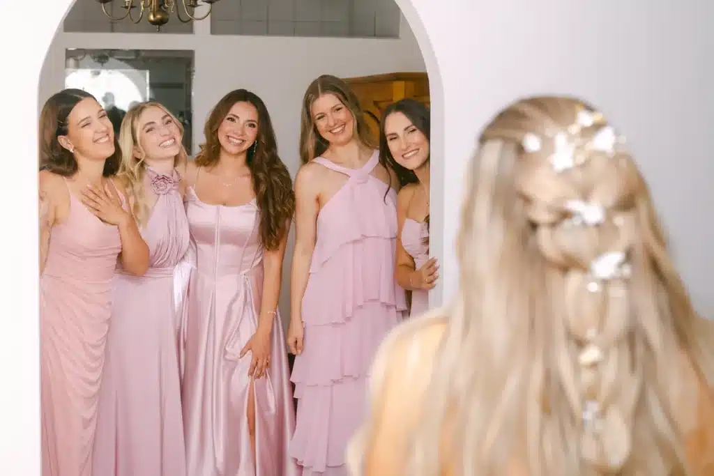 Fünf Brautjungfern in rosa Kleidern sehen die Braut zum ersten Mal im Brautkleid