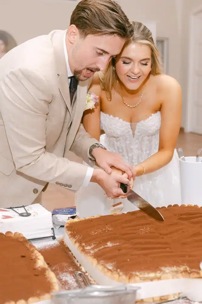 Brautpaar schneidet gemeinsam das Tiramisu mit einem großen Messer an