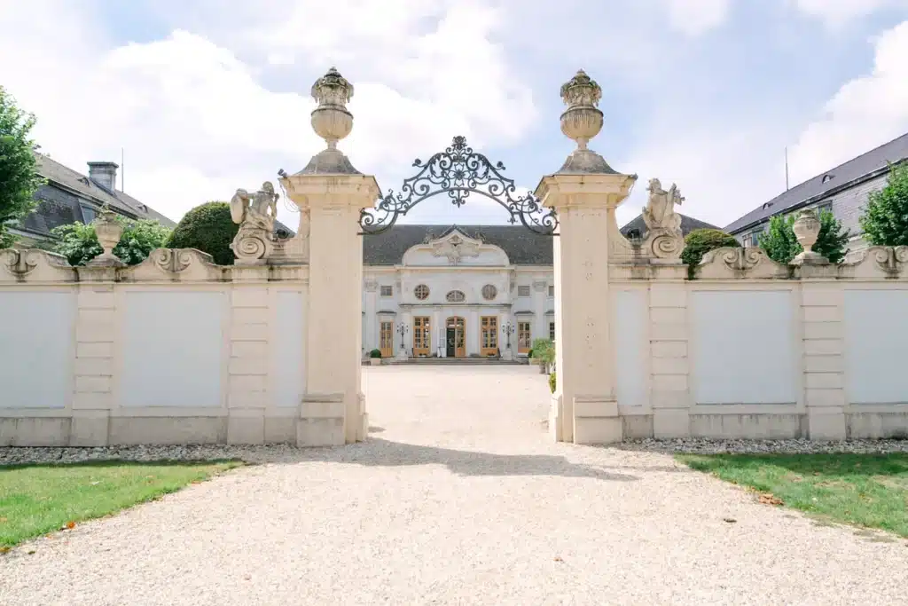 Schmiedeeisernes Eingangstor mit Steinpfeilern und Blick auf Schloss Halbturn