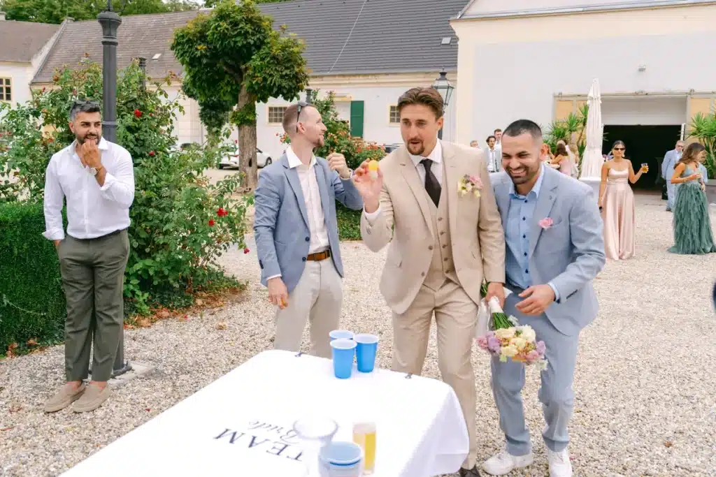 Bräutigam wirft beim Bierpong im Hof, Freunde schauen zu